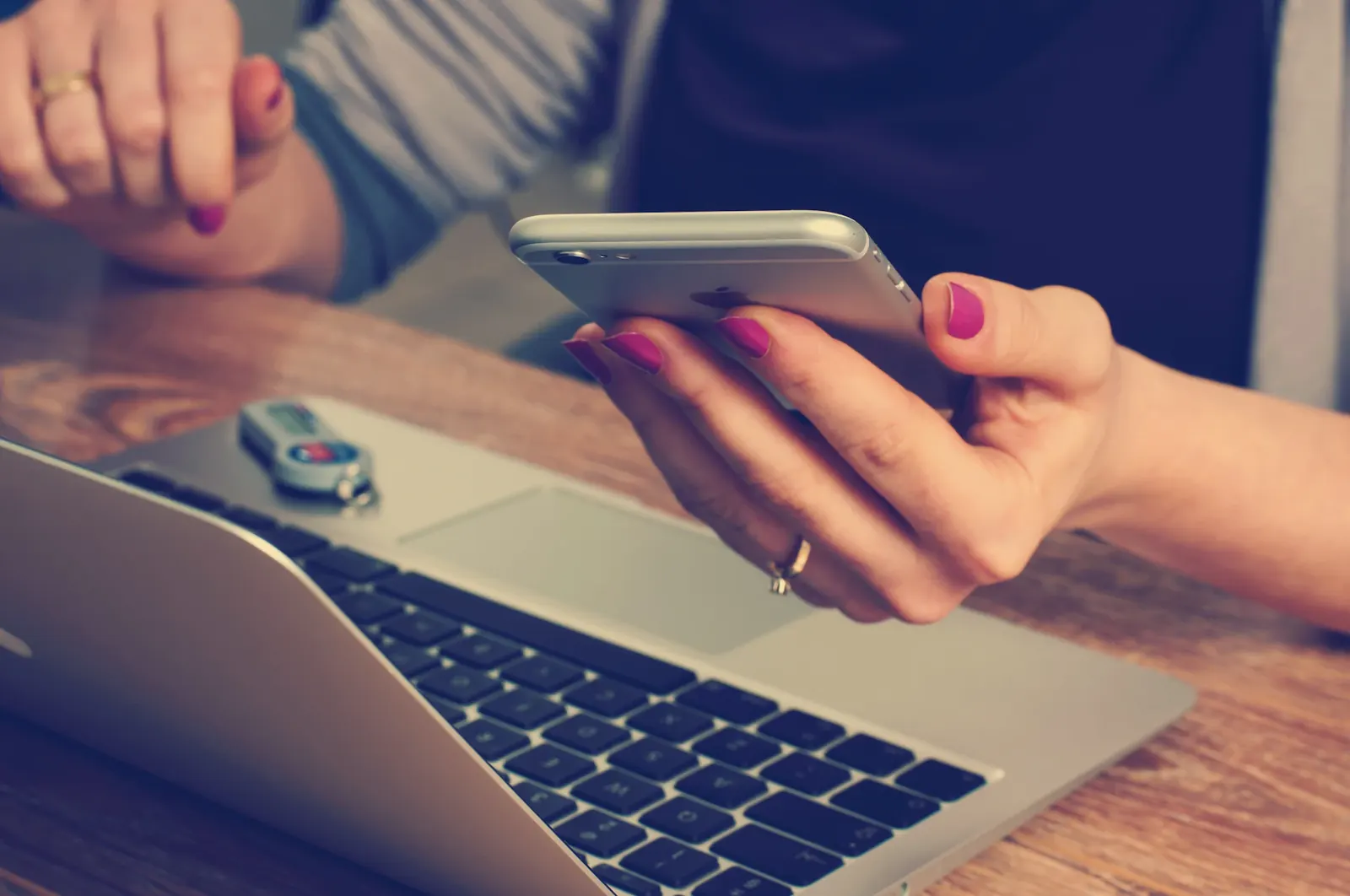 Personne consultant son smartphone devant un ordinateur portable